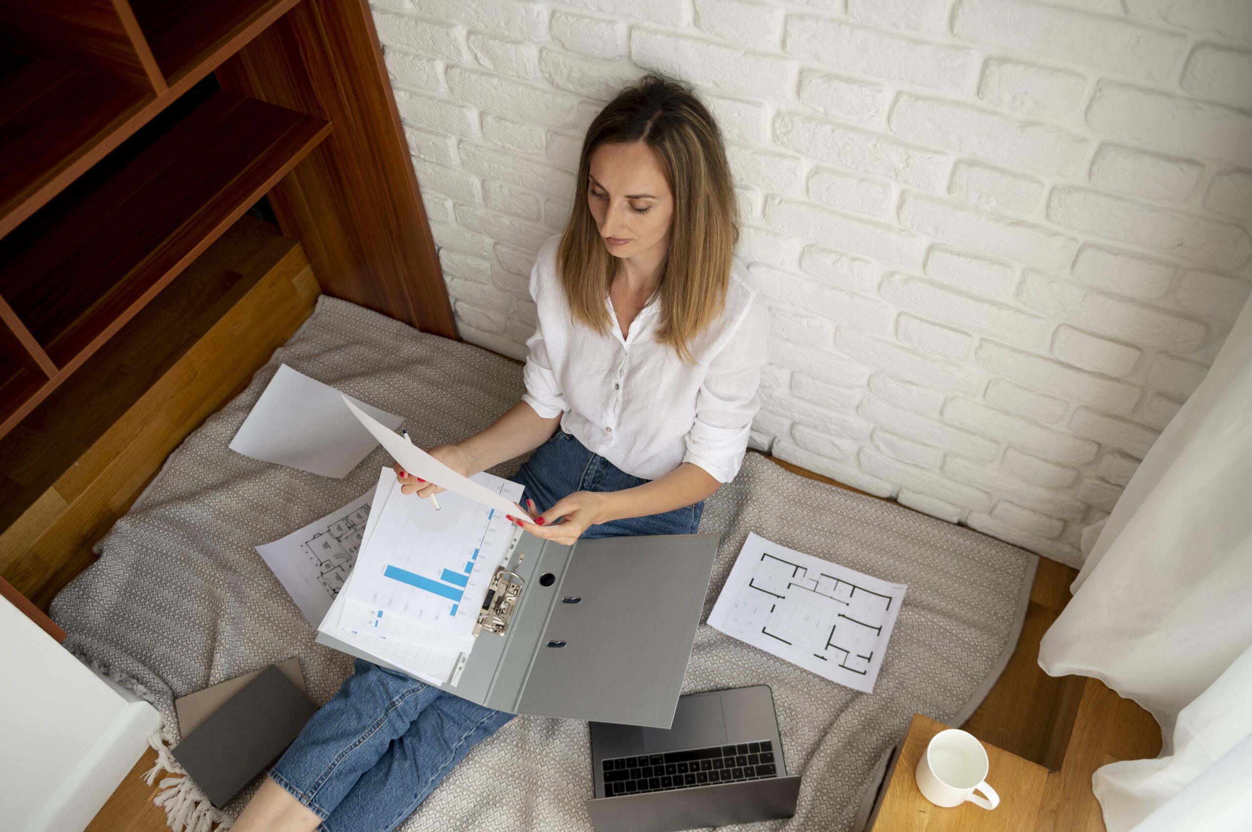 Woman reviewing documents and charts on a laptop, focusing on time management and organization for effective remote work.